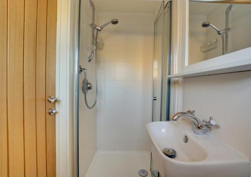 een witte badkamer met een wastafel en een douche bij Marsh View in Salthouse