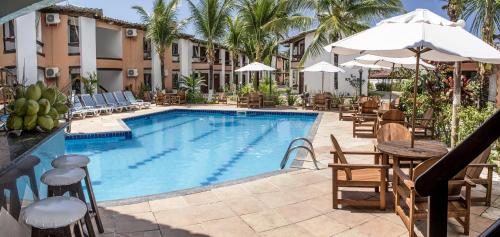 a swimming pool with tables and chairs and a hotel at Arraial do Sol Beach Hotel in Arraial d'Ajuda