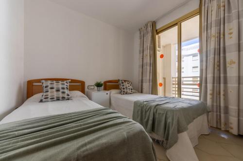 two beds in a room with a window at Apartamentos Novelty Arysal in Salou