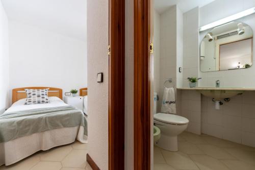 a bathroom with a bed and a toilet and a sink at Apartamentos Novelty Arysal in Salou