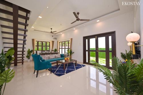 a living room with a couch and a blue chair at EKOSTAY Luxe - Oceanic Villa in Alibaug