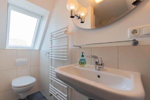a bathroom with a sink and a toilet and a mirror at Hus Mattgoot - private Einzelzimmer im DG und 1 OG in Ording
