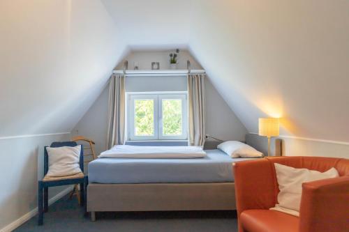1 dormitorio con cama, ventana y silla en Hus Mattgoot - private Einzelzimmer im DG und 1 OG, en Ording