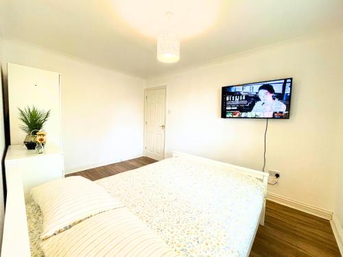 a bedroom with a bed and a tv on the wall at A Lovely Home Stay Near Greenwich in London