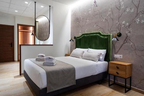 een slaapkamer met een bed met een groen hoofdeinde en een spiegel bij Complejo Valle Grande in Zarza la Mayor