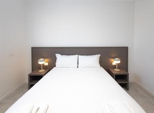 um quarto com uma grande cama branca e 2 candeeiros em The Residence 2.0 em Galliate