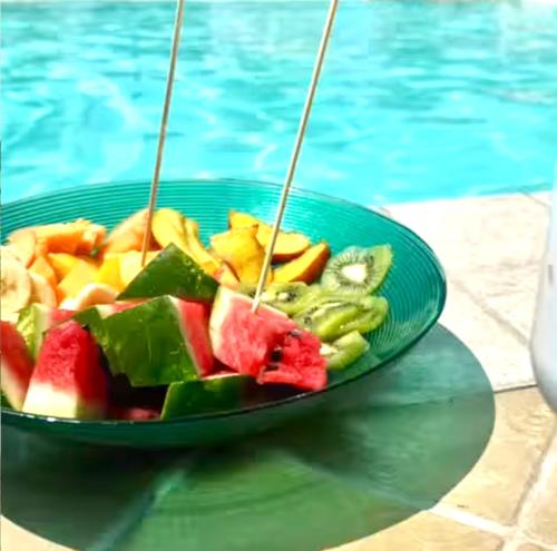 a plate of fruit and vegetables next to a swimming pool at La Siègià Resort spa in Massa Marittima
