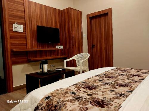 Schlafzimmer mit einem Bett, einem Schreibtisch und einem TV in der Unterkunft HOTEL KANAL KOTA in Kota
