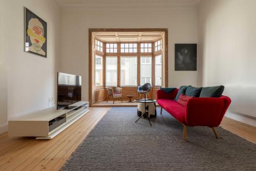 een woonkamer met een rode bank en een tv bij Spacious Belle Epoque House with free parking in Oostende