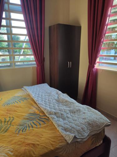a bed in a bedroom with red drapes and a window at ABHAR Inap Desa in Alor Setar