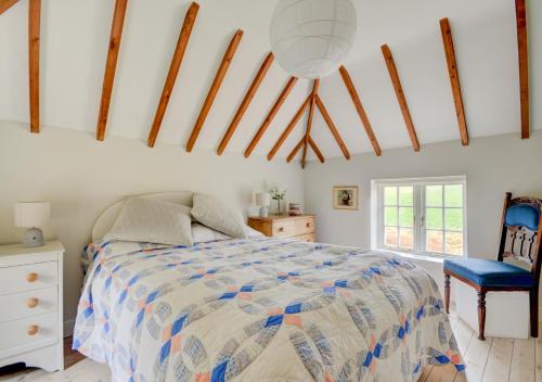 a bedroom with a bed and a blue chair at Aurora Cottage in Little Barningham