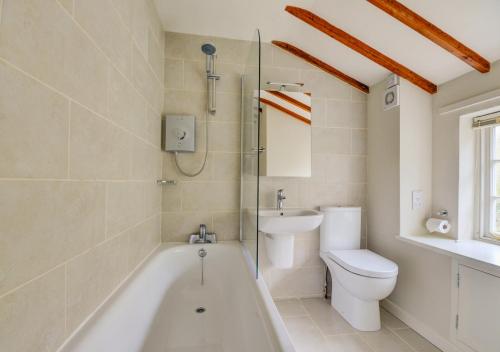 a bathroom with a tub and a toilet and a sink at Aurora Cottage in Little Barningham