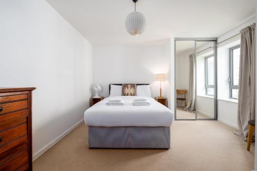 a white bedroom with a bed and a mirror at GuestReady - Bow luxury haven in London