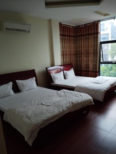 two beds sitting in a room with a window at Nhà nghỉ Thành Đạt in Hai Phong