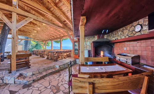 a large room with a fireplace and tables and benches at Apartments & Bungalows Ivanović in Kaštela