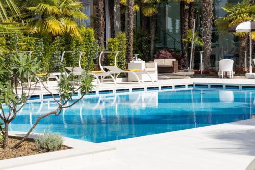 einen Pool mit Liegestühlen und ein Resort in der Unterkunft Hotel Garda - TonelliHotels in Riva del Garda