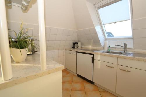 cocina blanca con fregadero y ventana en Watthaus 4 -zwischen Wattenmeer und Nordseestarnd, en Rantum