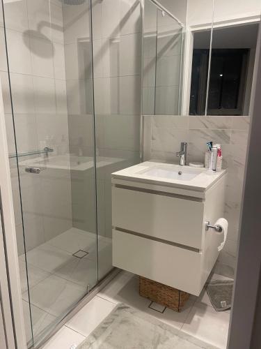a white bathroom with a sink and a shower at Perfect City View and gorgeous apartment in Melbourne