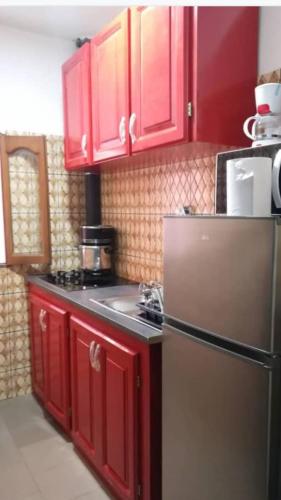 a kitchen with red cabinets and a stainless steel refrigerator at Résidences la Diaspora in Yaoundé