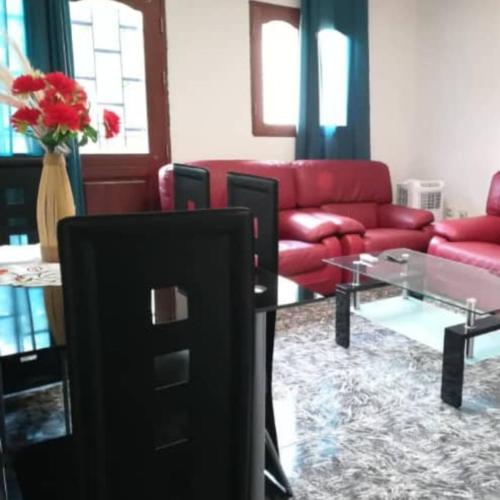 a living room with a red couch and a glass table at Résidences la Diaspora in Yaoundé