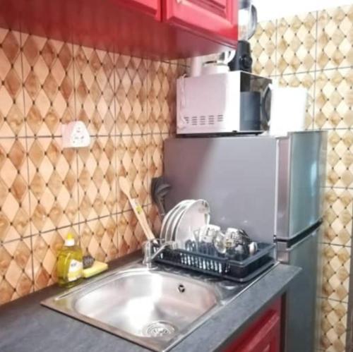 a kitchen sink with a microwave on top of it at Résidences la Diaspora in Yaoundé