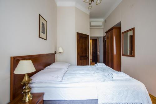 sypialnia z dużym białym łóżkiem z lampką w obiekcie Aparthotel Basztowa w Krakowie