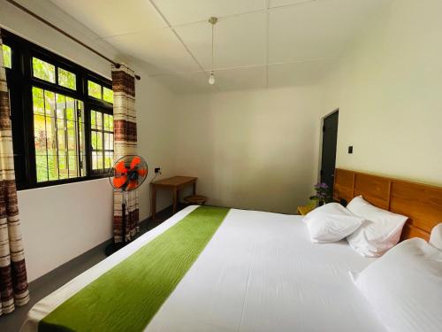 - une chambre avec un grand lit blanc et une fenêtre dans l'établissement 1818 Badulla, à Badulla