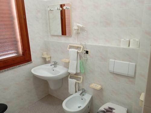 a white bathroom with a sink and a toilet at Hotel Meridiana in Arbus