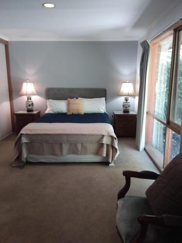a bedroom with a bed with two lamps and a couch at Hobreid Park in Woodend