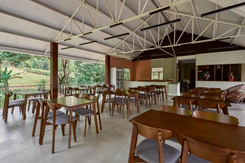 a restaurant with wooden tables and chairs and windows at Baan Rai Santisuk in Ban Sok Dua