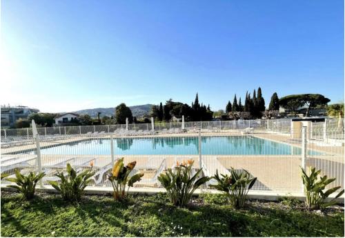 une grande piscine entourée d'une clôture. dans l'établissement Appartement 312 supérieur - LES SUITES DE ROBINSON - Résidence avec piscine en bord de Siagne, à Mandelieu-La-Napoule, à Mandelieu-la-Napoule