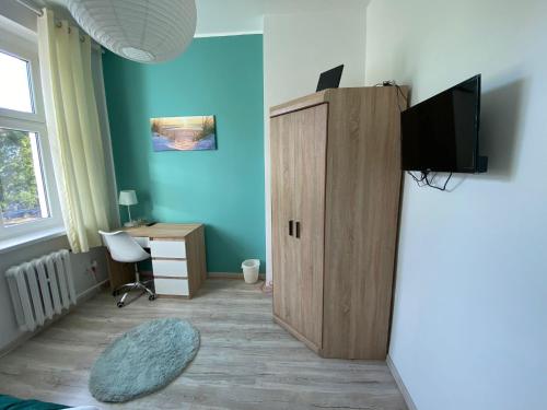 Habitación con armario de madera y escritorio con TV. en Magnolia 2, en Toruń