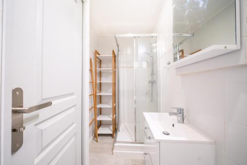 une salle de bain blanche avec un lavabo et un miroir dans l'établissement Le Lucia, Beau T2, Clim,Centre Historique, Comédie, à Montpellier