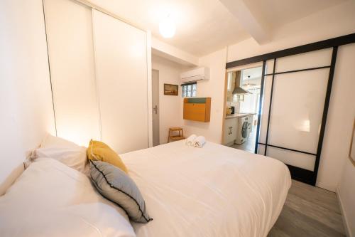 un lit blanc dans une chambre avec une fenêtre dans l'établissement Le Lucia, Beau T2, Clim,Centre Historique, Comédie, à Montpellier