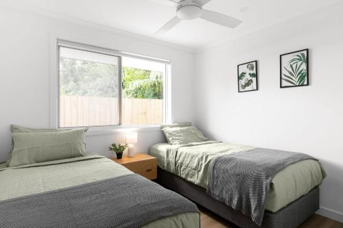 a bedroom with two beds and a window at Amiri on Holbrook - Pet Friendly in Yaroomba