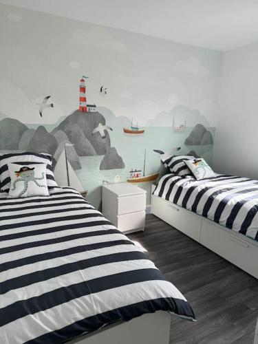 - une chambre avec 2 lits et un phare sur le mur dans l'établissement Maison La méduse, à Quettehou