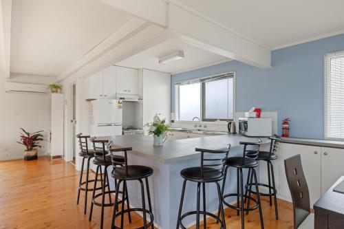 a kitchen with a bar with stools in it at Quiet Holiday Home in Surf Beach VIC in Surf Beach