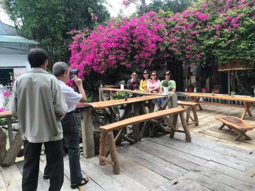 een man die een foto neemt van een groep mensen die aan tafel zitten bij Homestay Minh Ngọc in Ban Hin Lom