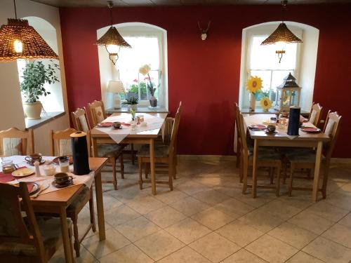 a dining room with tables and chairs and windows at Pension Scherzer in Ohorn