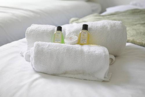 dos toallas en una cama con dos botellas de jabón en StayRight 2 Bed House - Quick Drive to Brecon Beacons & more, en Griffithstown