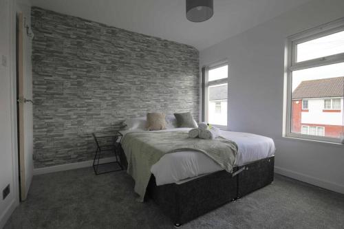 Un dormitorio con una pared de ladrillo y una cama en StayRight 2 Bed House - Quick Drive to Brecon Beacons & more, en Griffithstown