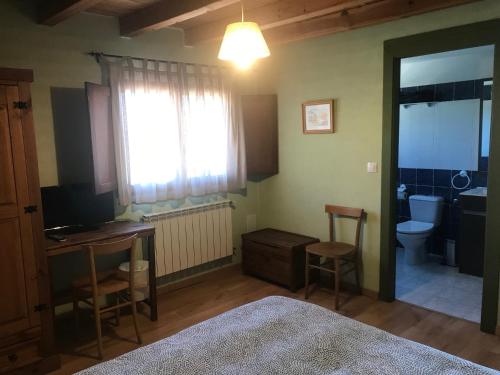 a bedroom with a bed and a desk and a toilet at Alojamientos Casa San Habitaciónes in Besande