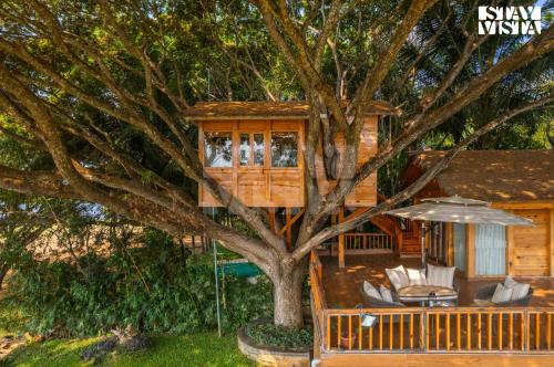 a tree house with chairs and an umbrella at StayVista at Exotica Kabini - All Meals Included in Antarasante