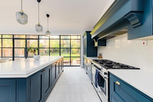 uma cozinha com armários azuis e bancadas brancas em Beautiful large luxury home in London em Sidcup