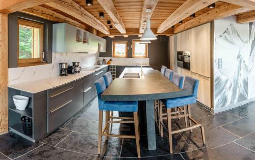 a kitchen with a table and some blue bar stools at Les Chalets d'Adelphine & SPA in Les Gets