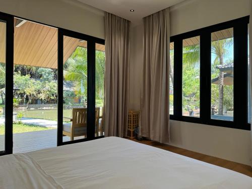 a bedroom with a large bed and large windows at Annhien home's in Ấp Long Thạnh
