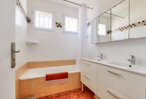 une salle de bain avec une baignoire, un lavabo et un miroir dans l'établissement Évasion en famille à Brem-sur-Mer, à Brem-sur-Mer