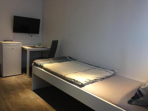 a bed in a room with a desk and a television at Einzelzimmer mit Bad in Zwickau