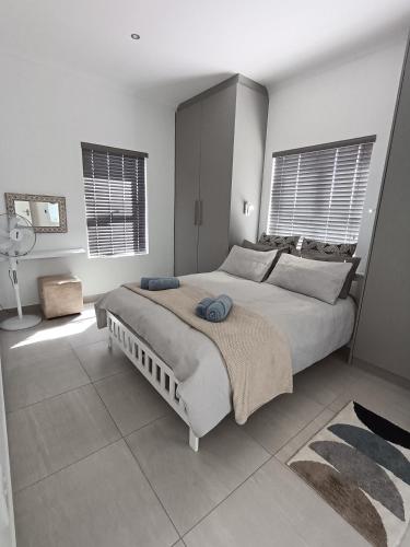 a bedroom with a large bed and two windows at Silver Oaks Luxury Guest Cottage in Langebaan