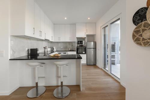 a kitchen with white cabinets and a counter with stools at Villa Lagoa in Vau
